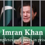 Imran Khan behind jail bars with a green banner reading "Imran Khan completes two years in prison