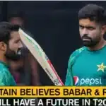 Two Pakistani cricketers, Babar Azam and Mohammad Rizwan, in training jerseys during a T20I match preparation, discussing strategy on the field.